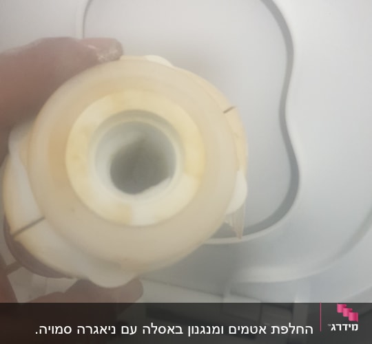 יד מחזיקה חלק פלסטיק מול אסלה לבנה